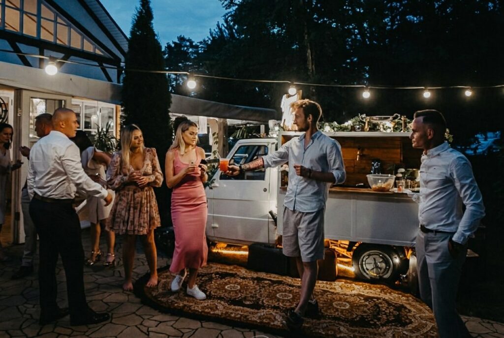 Goście przy barze mobilnym w świetle lampek wieczorem